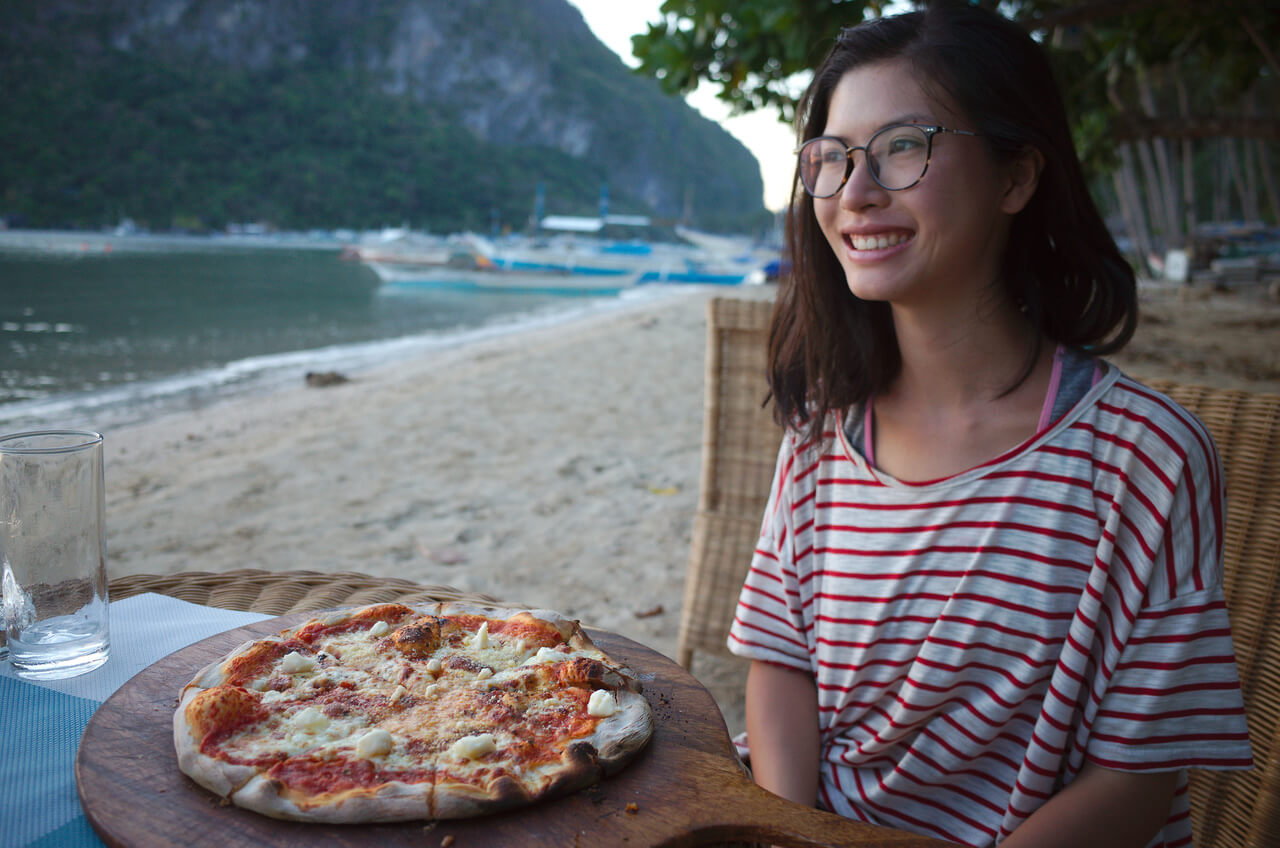 Clara pose avec notre pizza au bord de la mer à Coron Coron