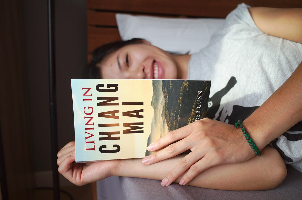 Clara rit en lisant Living in Chiang Mai de Alex Gunn