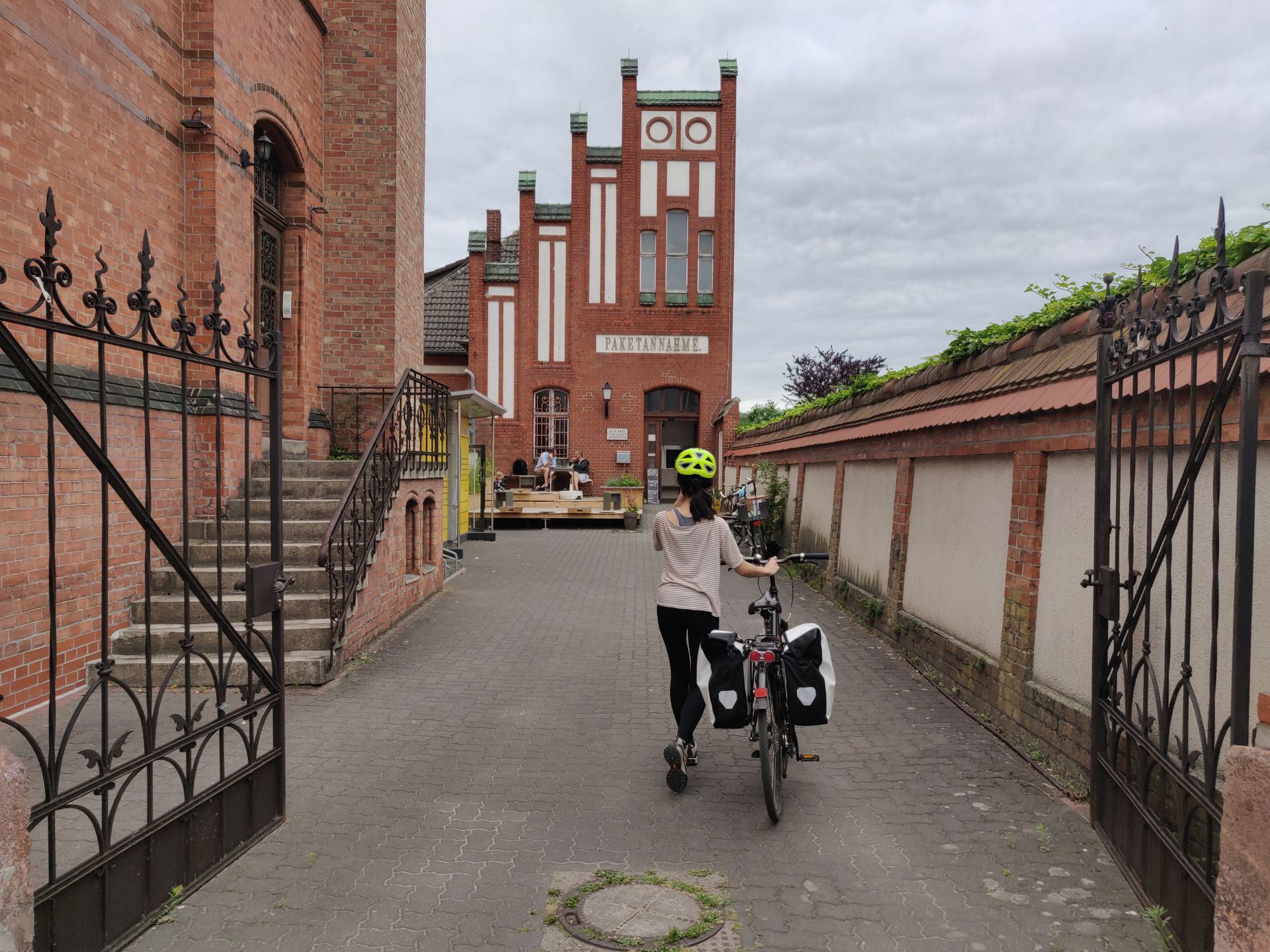 Clara arrive avec son vélo chargé de sacoches devant un café dans la vieille poste de Eberswalde