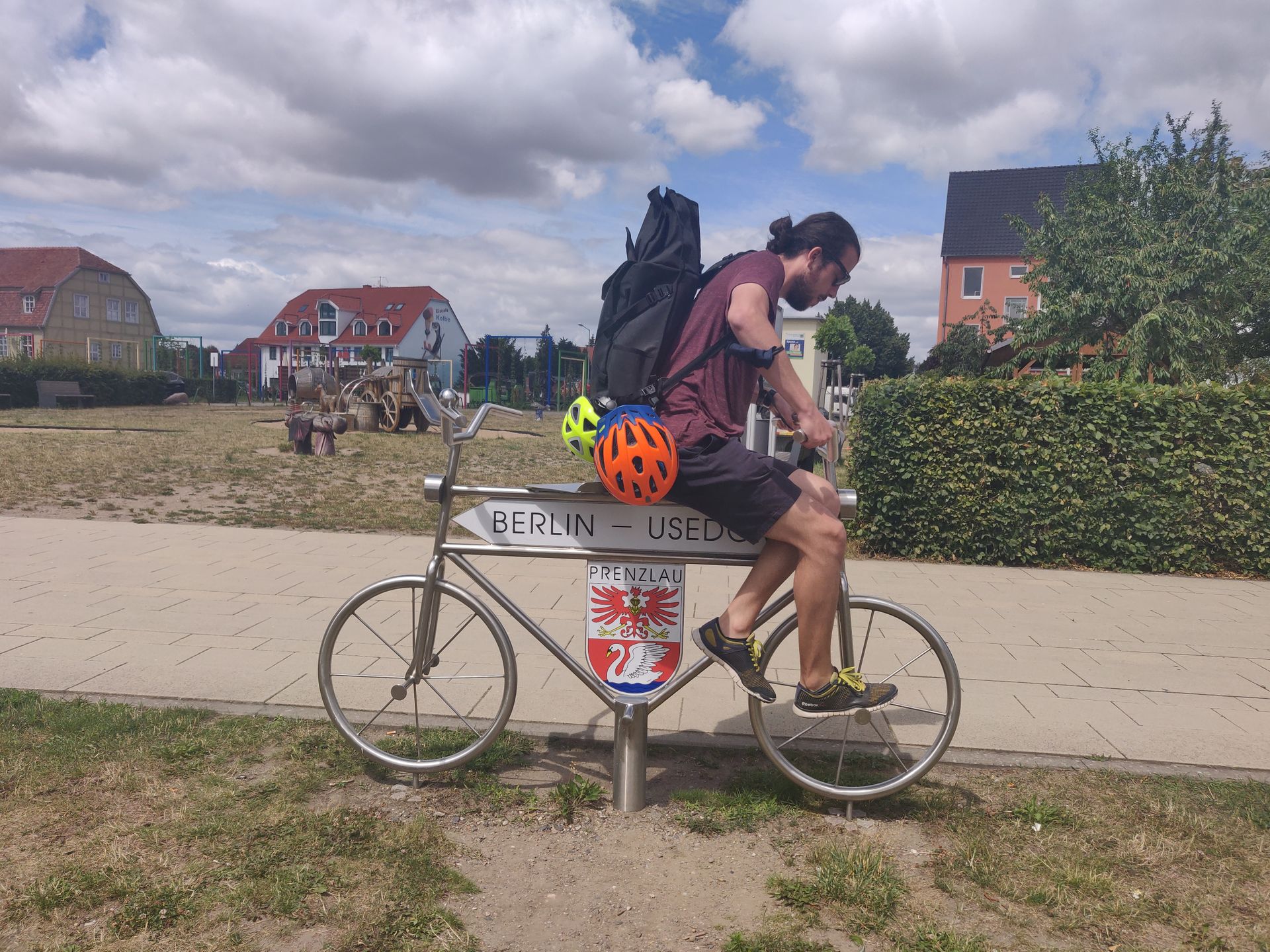 Robin sur un vélo-panneau qui indique Berlin et Usedom