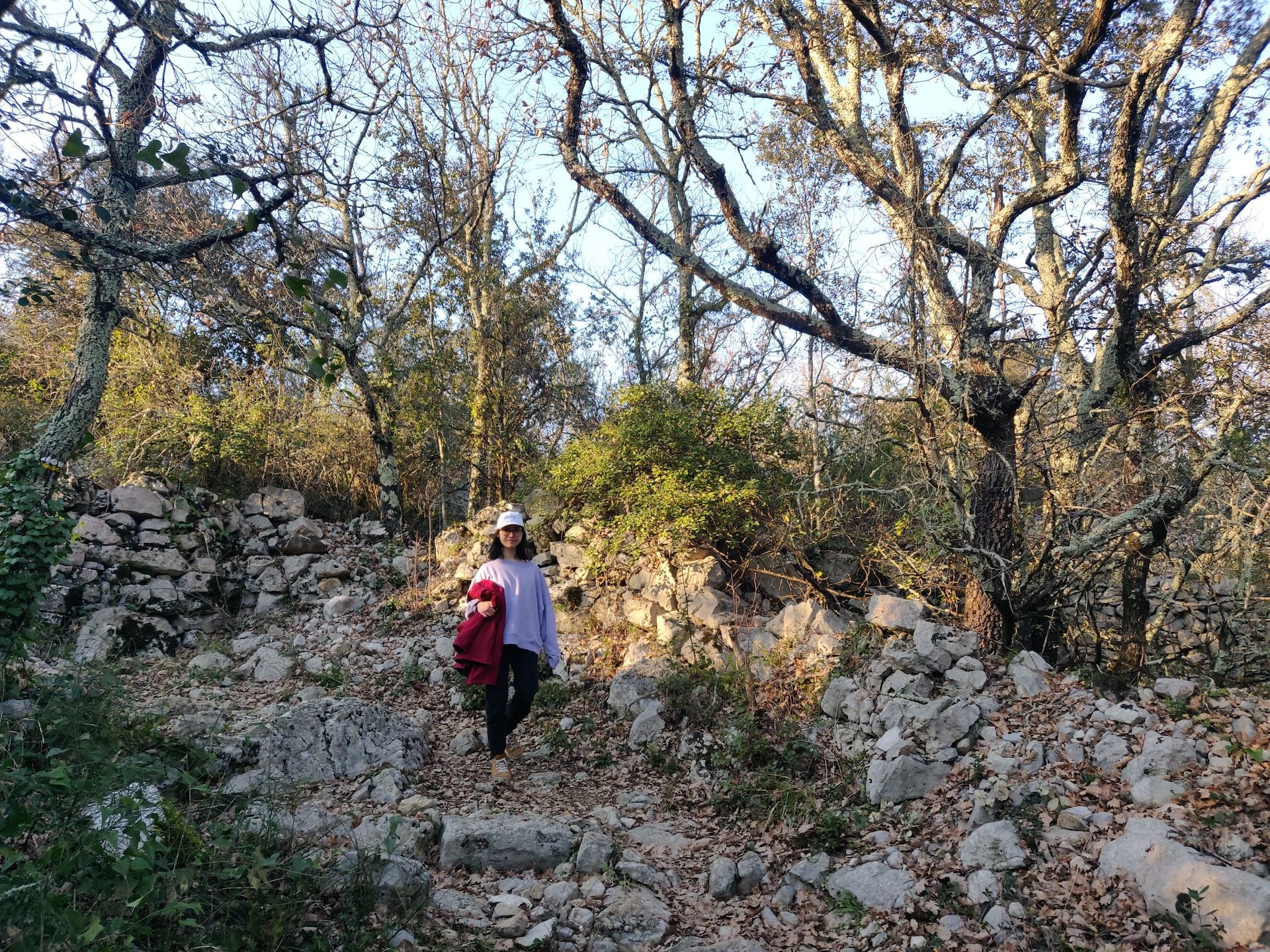 Clara descend le long d'un petit chemin de pierre dans le vallon qui mène au hamean de Servière, près de Balazuc