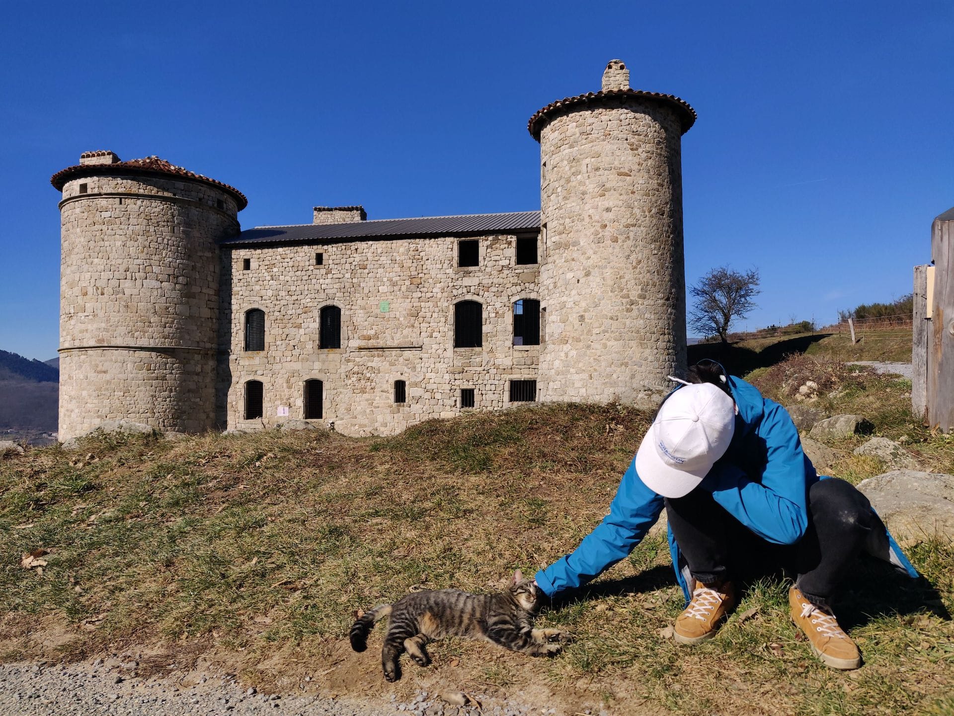Clara caresse le même chat devant le château de Craux