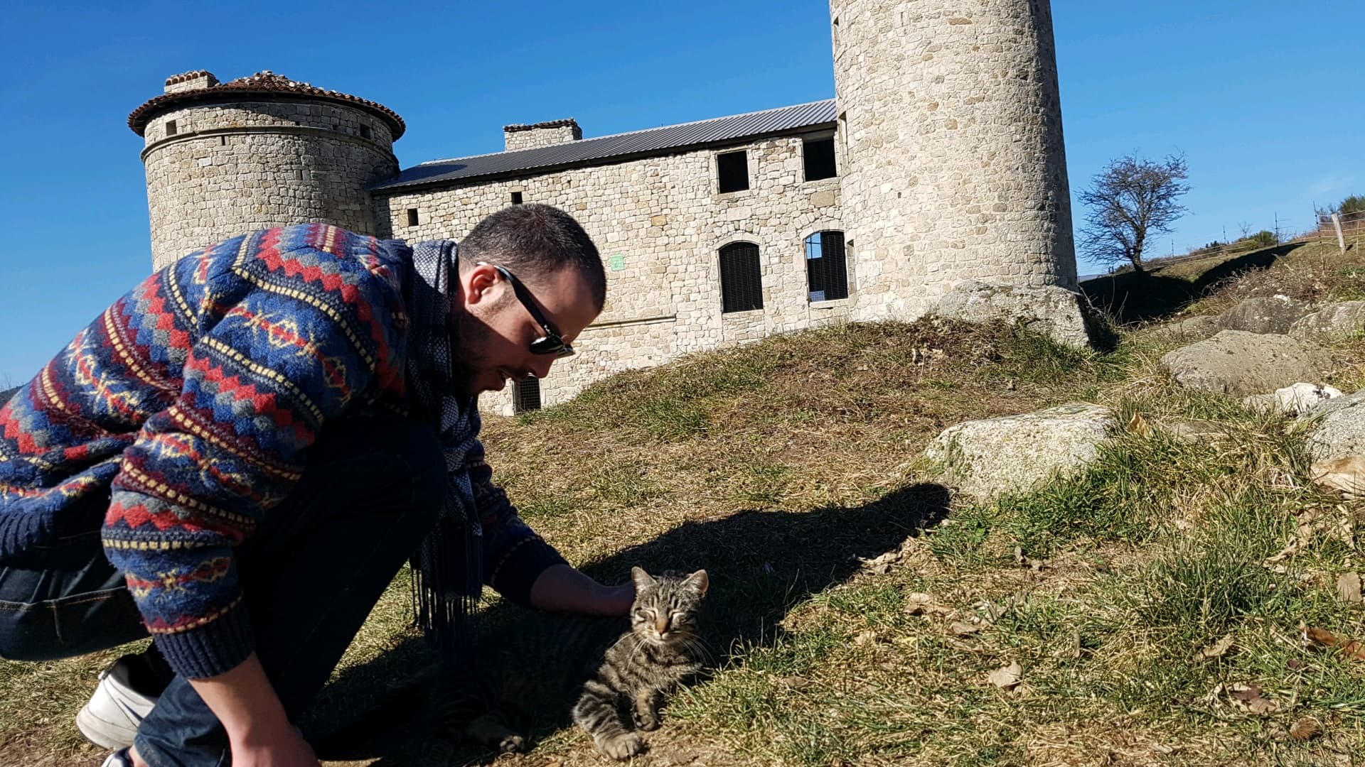 Robin caresse un chat devant le château de Craux