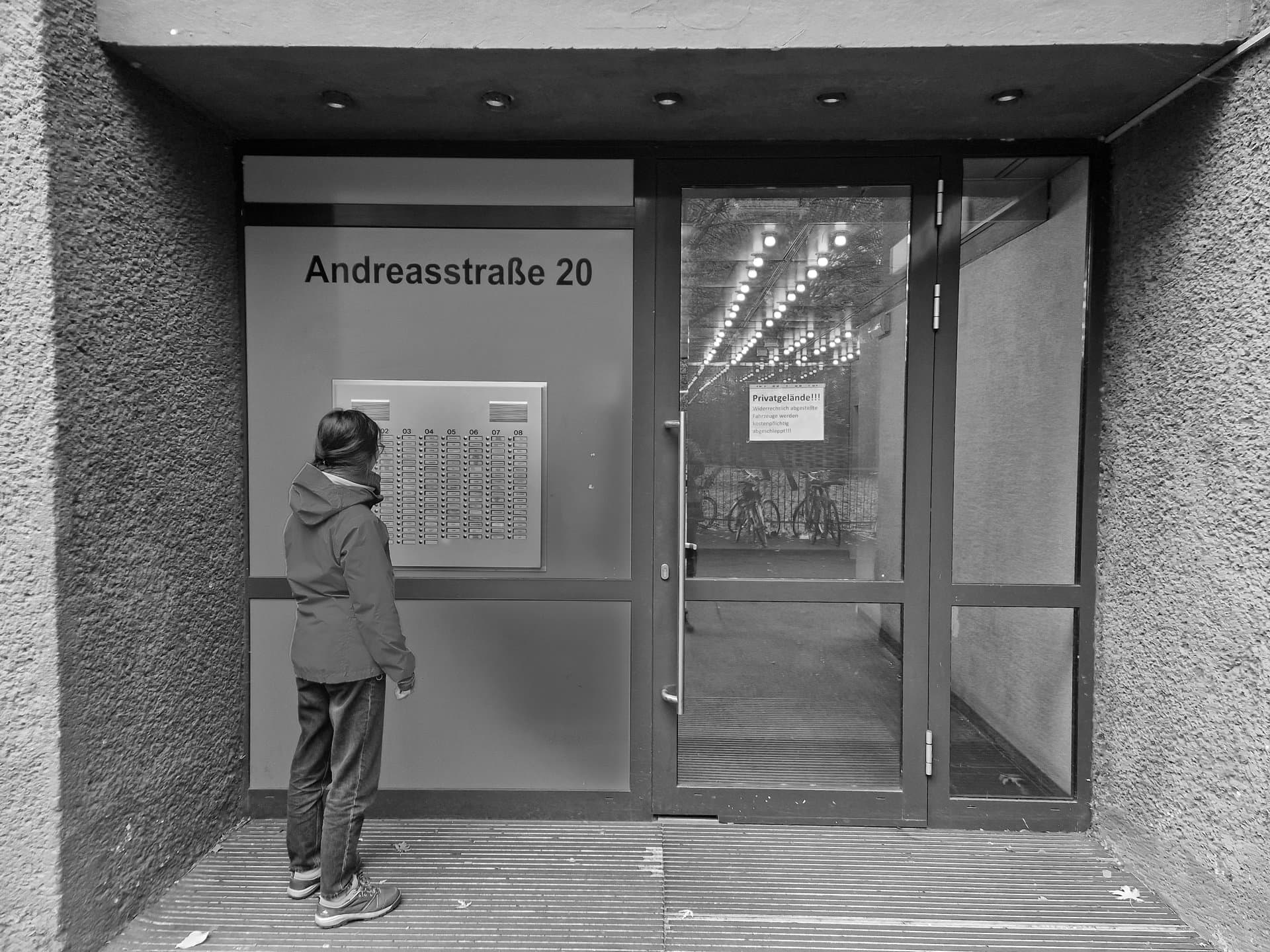 La porte d'entrée d'Andreastraße 20. Clara regarde les dizaines de boutons d'interphones du bâtiment.