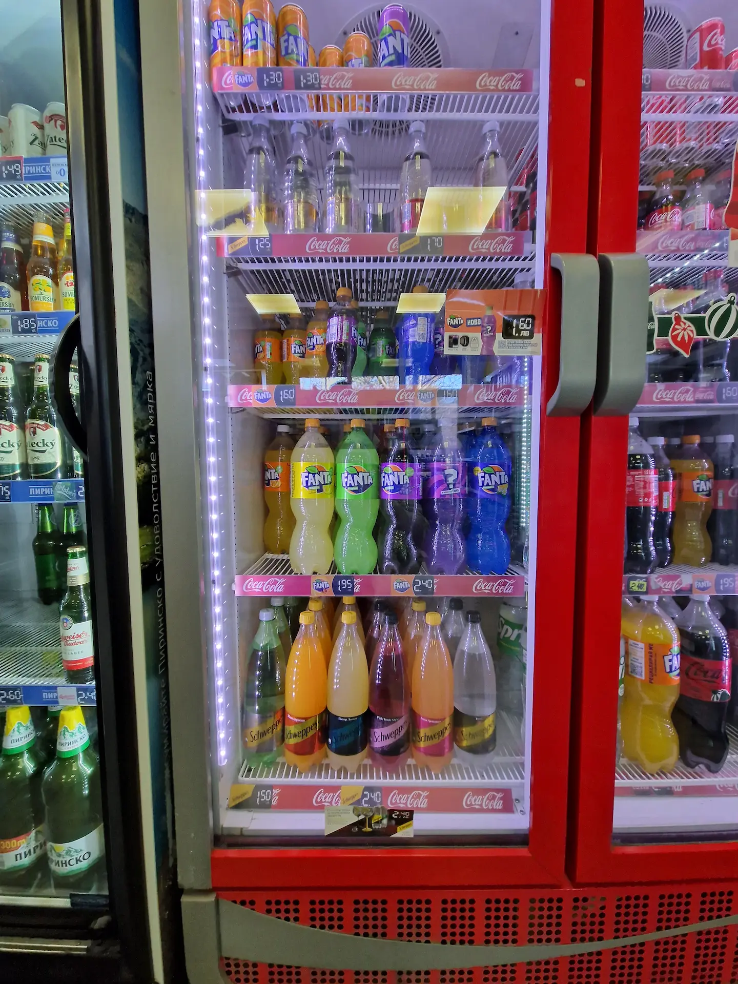 Un frigo rempli de sodas, dont un étage de bouteilles de Fanta de toutes les couleurs : orange, blanc, vert, noir, violet, bleu