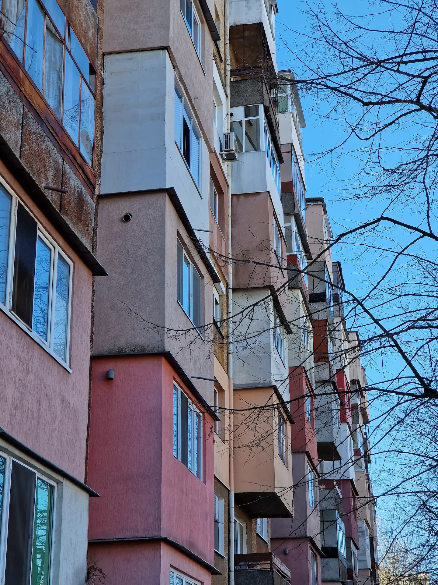 La façade d'un immeuble de béton avec des couleurs ternes, orange rouge brun.