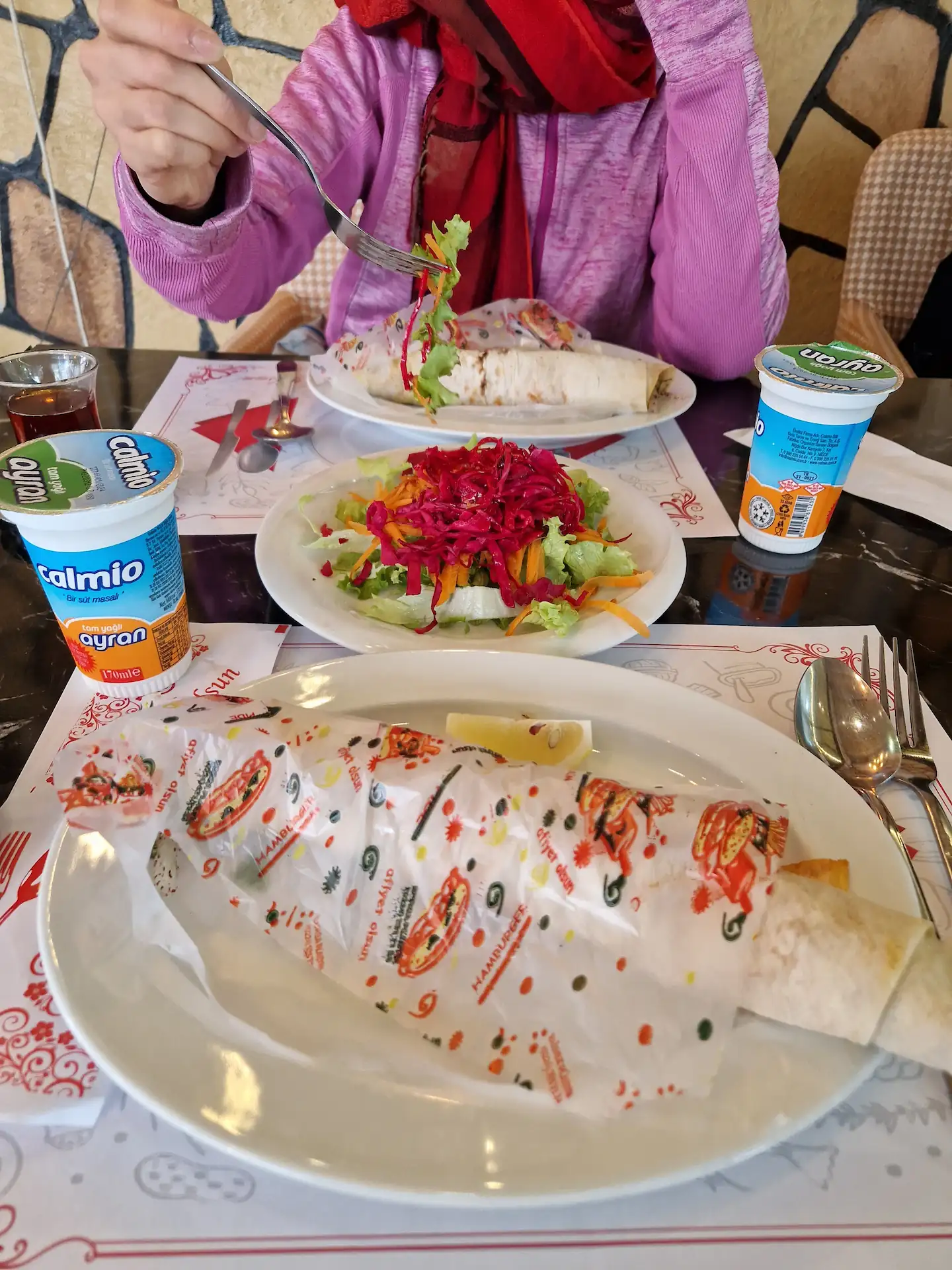 À une table pour deux, on voit deux assiettes où sont servis des tantuni avec un quartier de citron. Au milieu, une salade de crudités est à partager (Clara en pioche un peu).