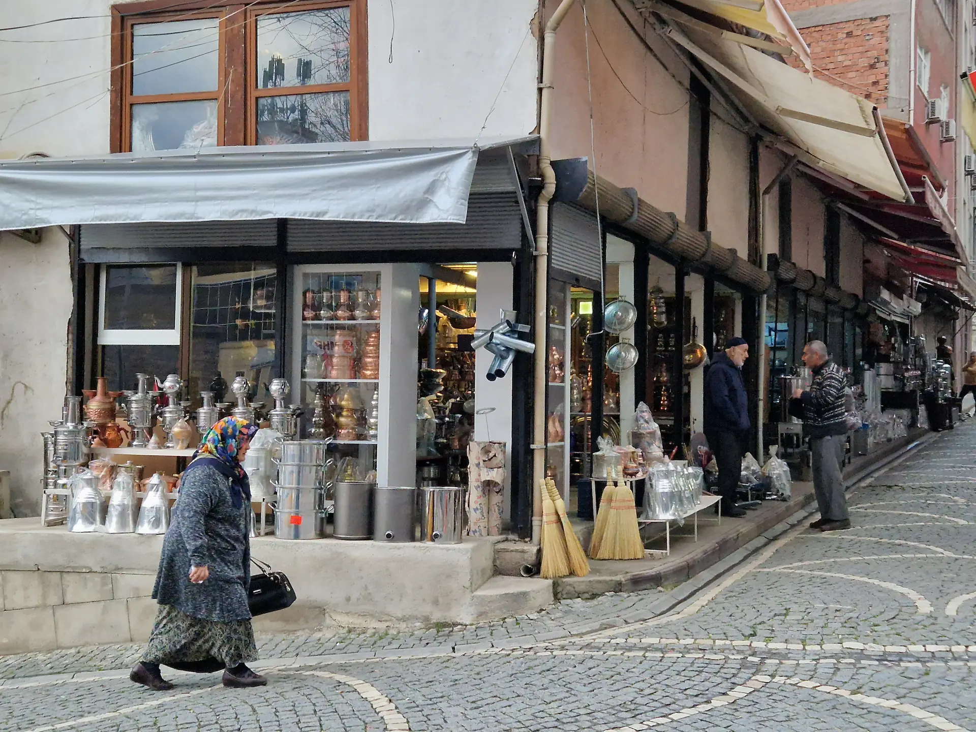 Un petit magasin de théières dans un coin de rue. Une vieille dame passe devant en marchant.