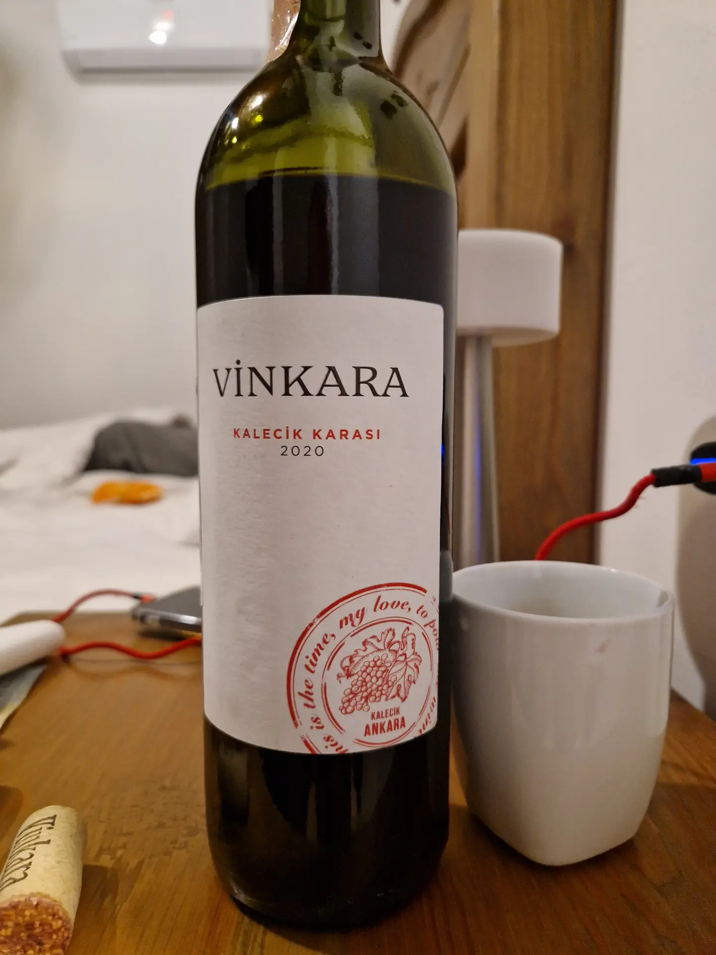 Une bouteille de vin rouge accompagnée de sa tasse de céramique
