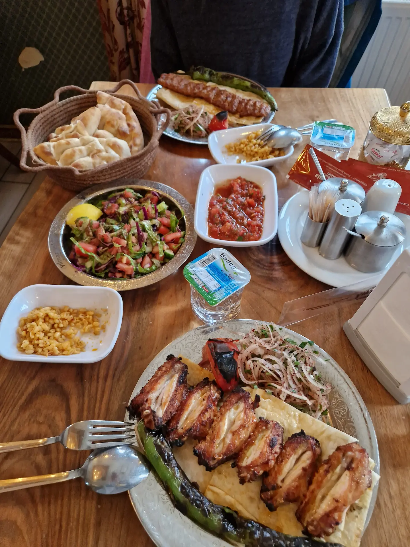 Sur la table : deux assiettes de kebabs et leurs accompagnements (salades, soupes, pains, etc.)