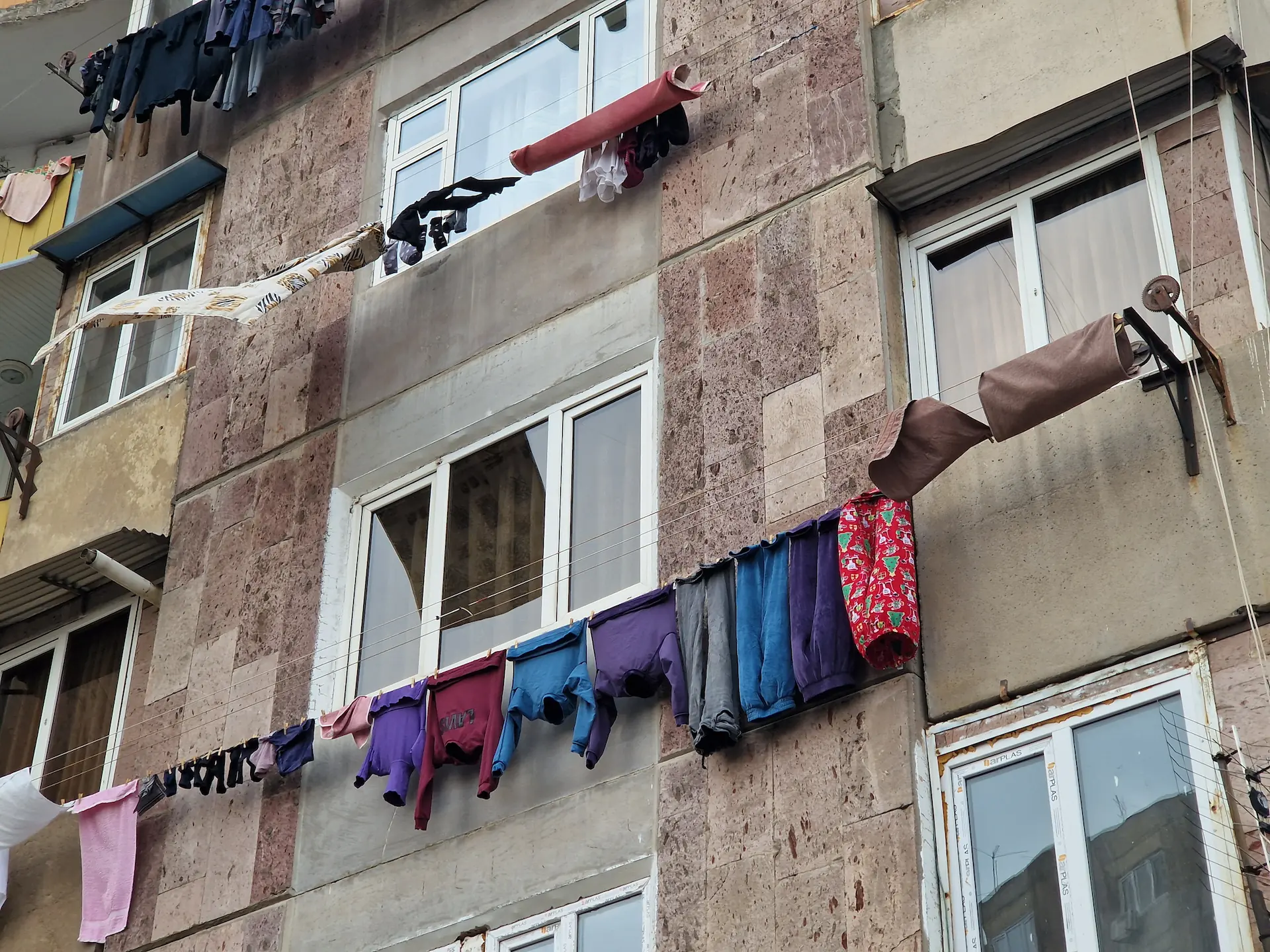 Des habits colorés sèchent sur des fils accrochés devant les fenêtres.