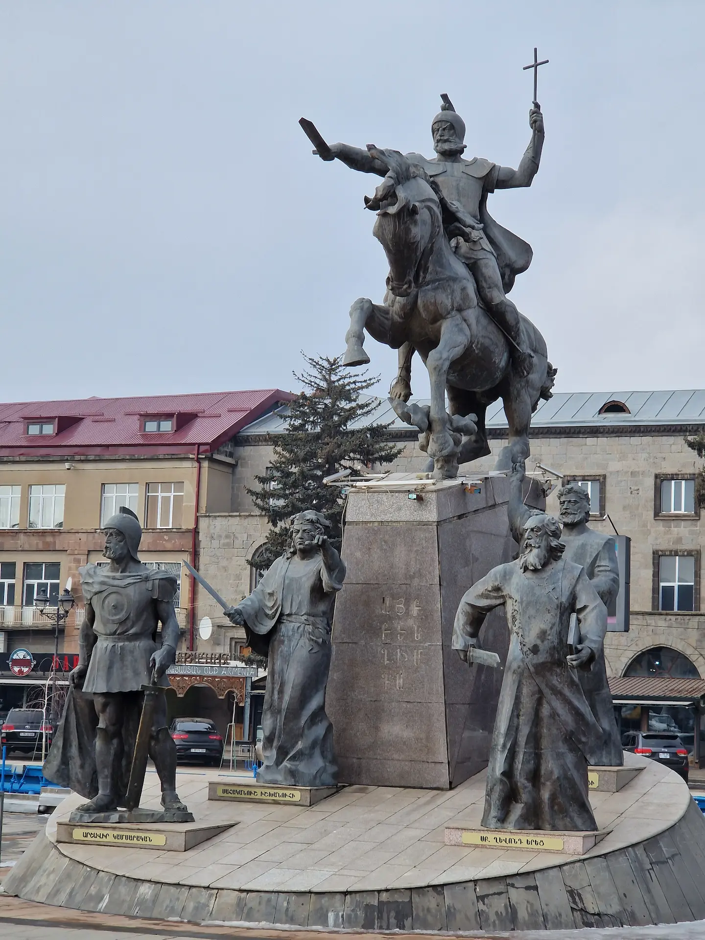 Une statue à Gyumri, un homme barbu à un cheval bradit une épée de sa main droite et une croix de sa main gauche. À ses pieds, quatre autres statues d'hommes d'église et leurs épées.