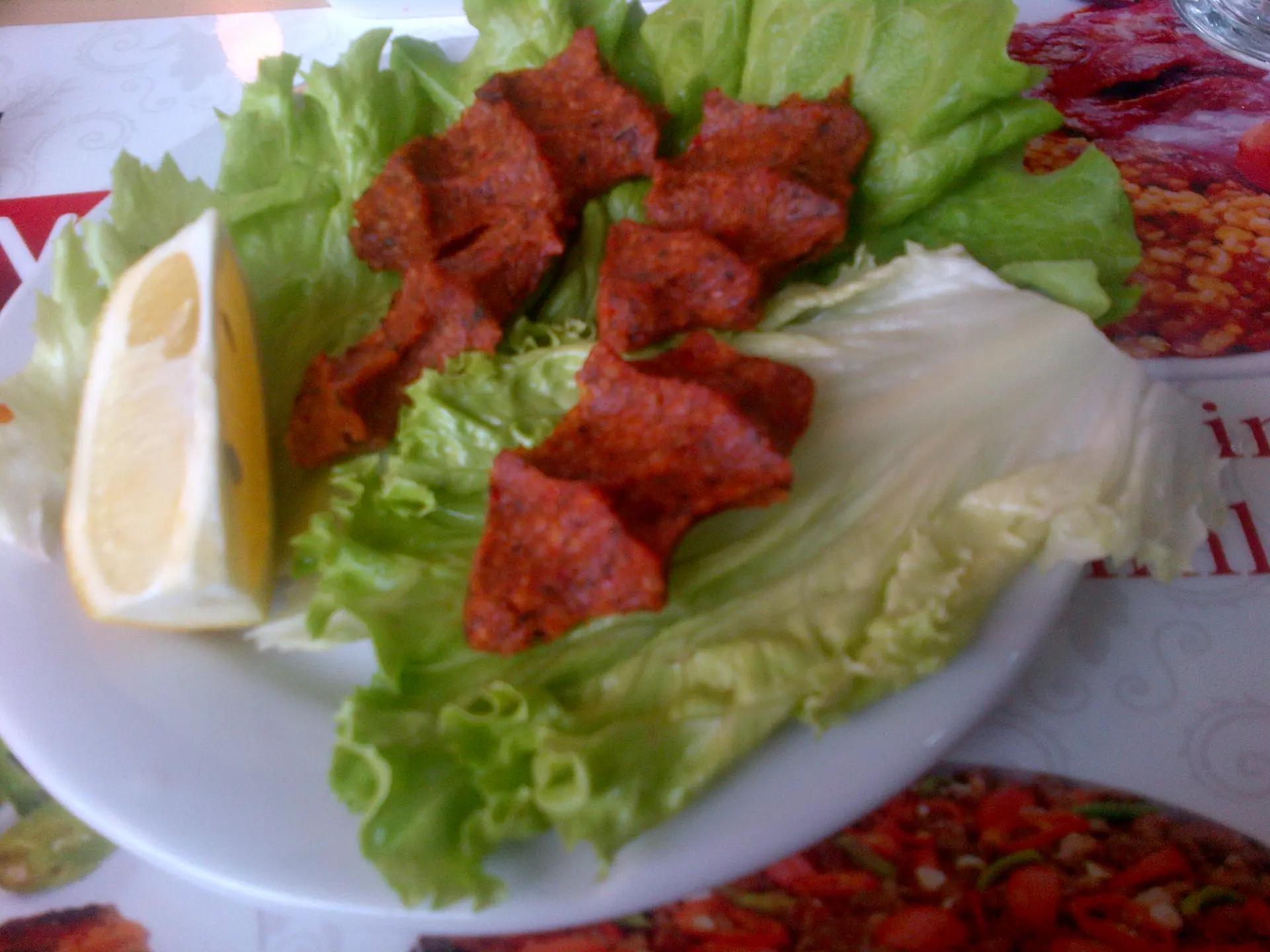 Un plat de çig köfte, des boulettes de roses-rouges pressées à la main et disposée sur une assiette avec un peu de citron.