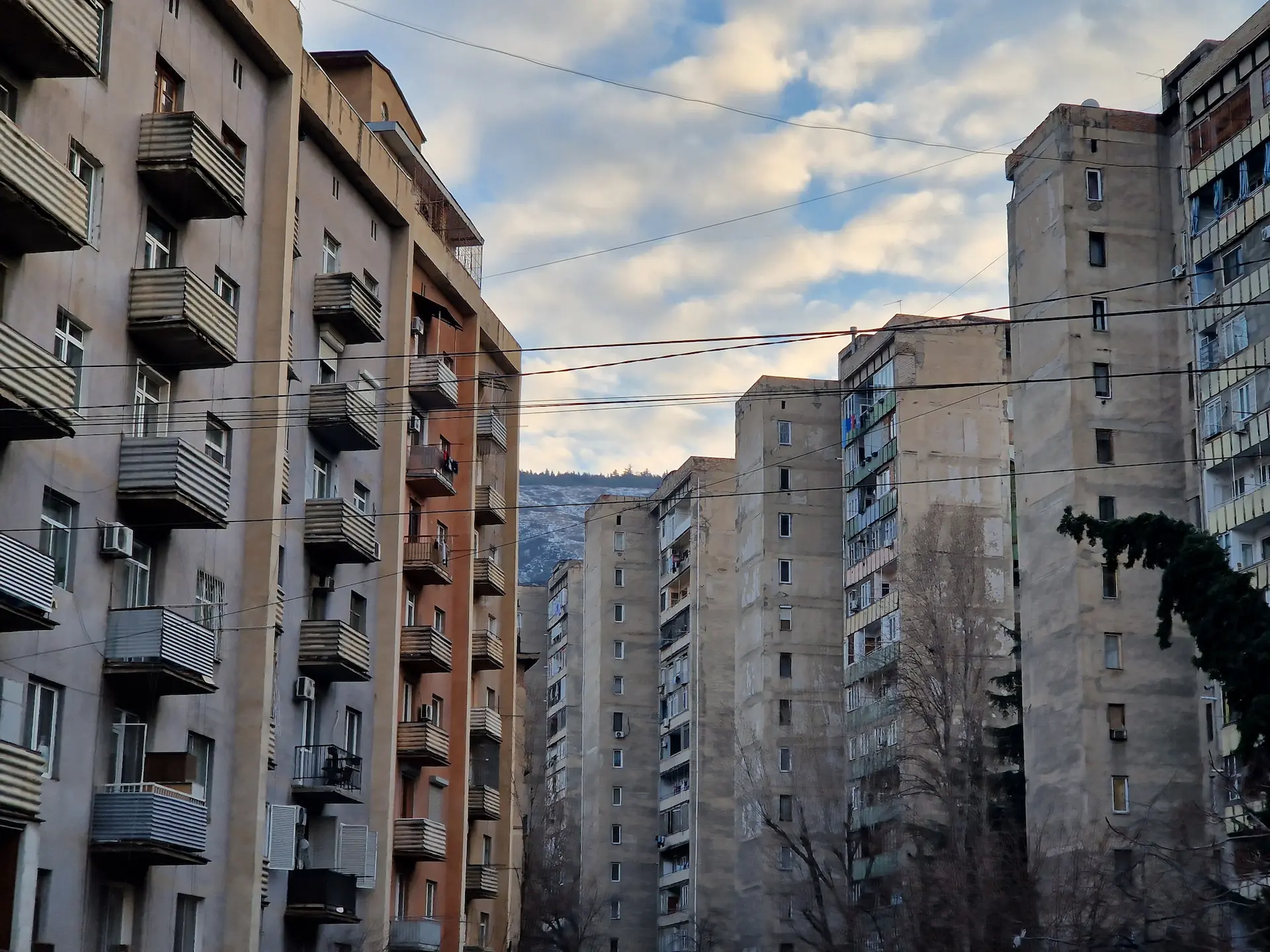 Un bloc de bâtiments soviétiques, avec une vue sur les montagnes en fond.