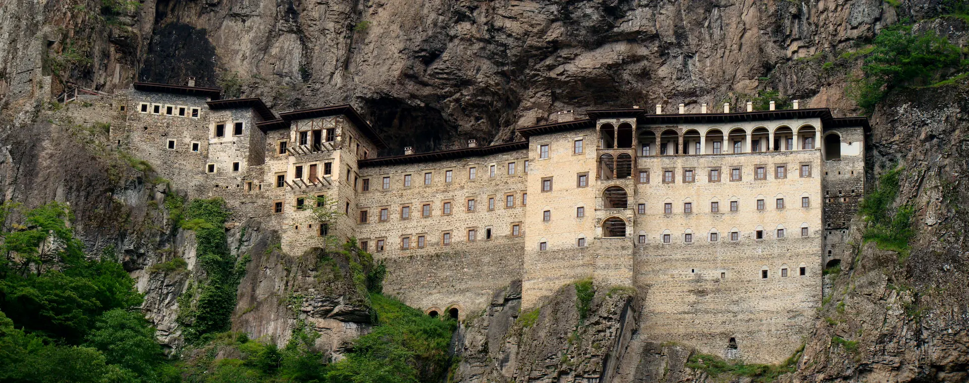Le monastère de Sümela, on voit des bâtiments avec plusieurs étages de fenêtres accrochés à une falaise.