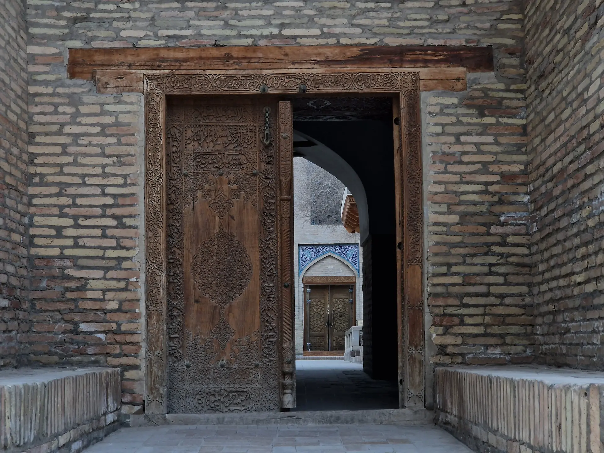Une grande porte en bois entrouverte laisse voir sa cour intérieure