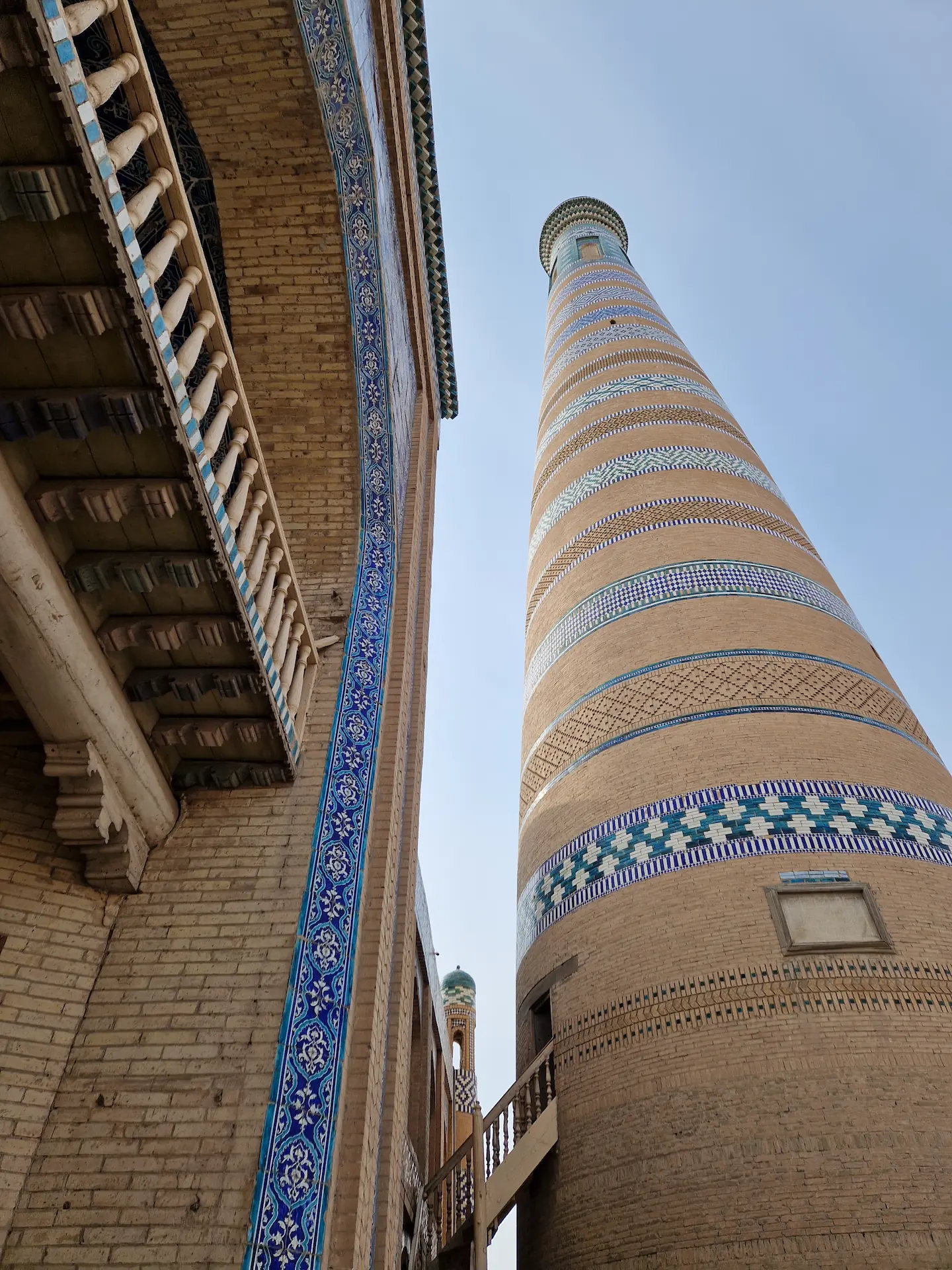 Un grand minaret vu de sa base, des bandes de motifs bleus décorent la colonne jusqu'à son sommet