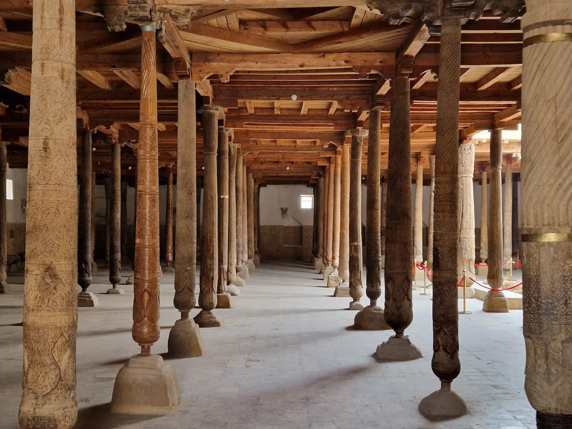 Intérieur d'une mosquée tout en bois. De nombreux piliers en bois soutiennent le bâtiment.