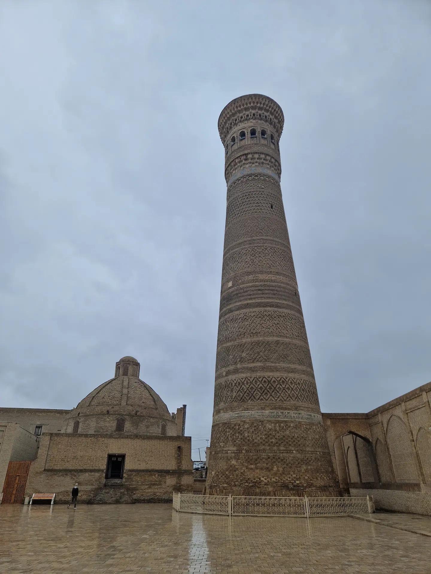 La minaret de Boukhara de briques couleur sable, large, imposant, sous un ciel gris.