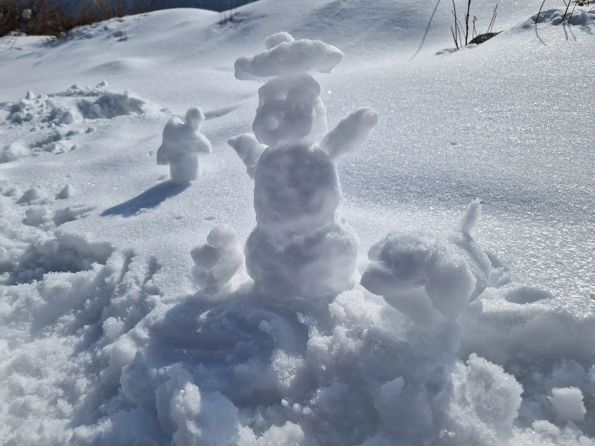 Un petit bonhomme de neige avec un chapeau, une maison, et un chien