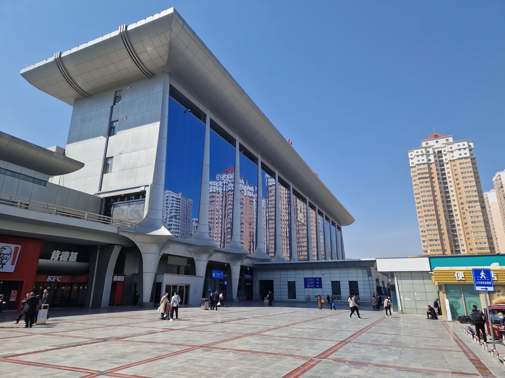 Le bâtiment vitré de la gare centrale de Lanzhou, où se reflètent des tours d'habitation.