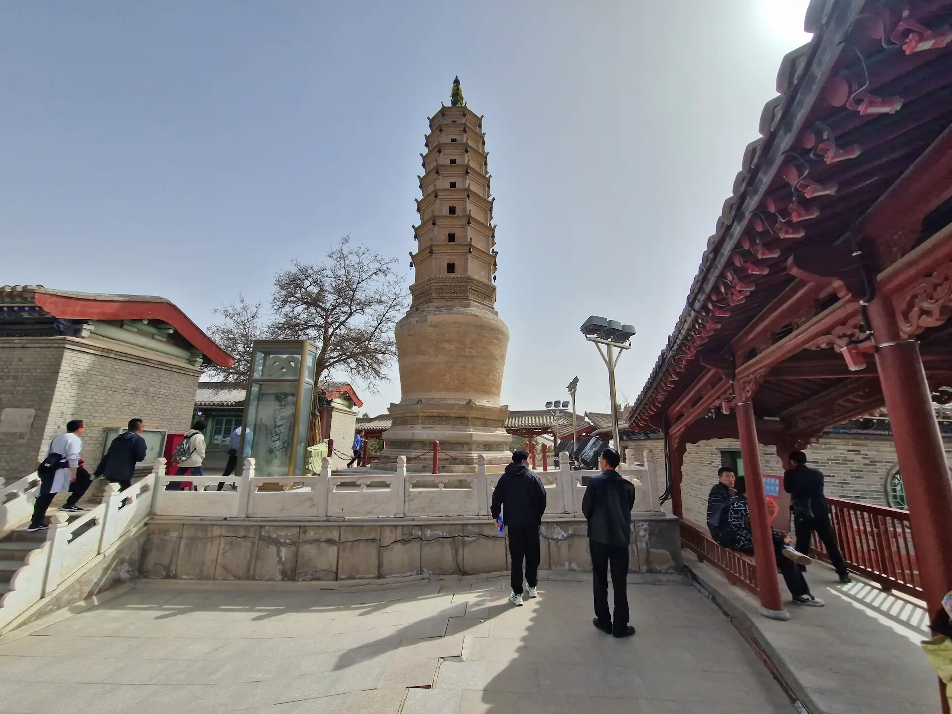 Une pagode de briques et quelques personnes qui prennent des photos
