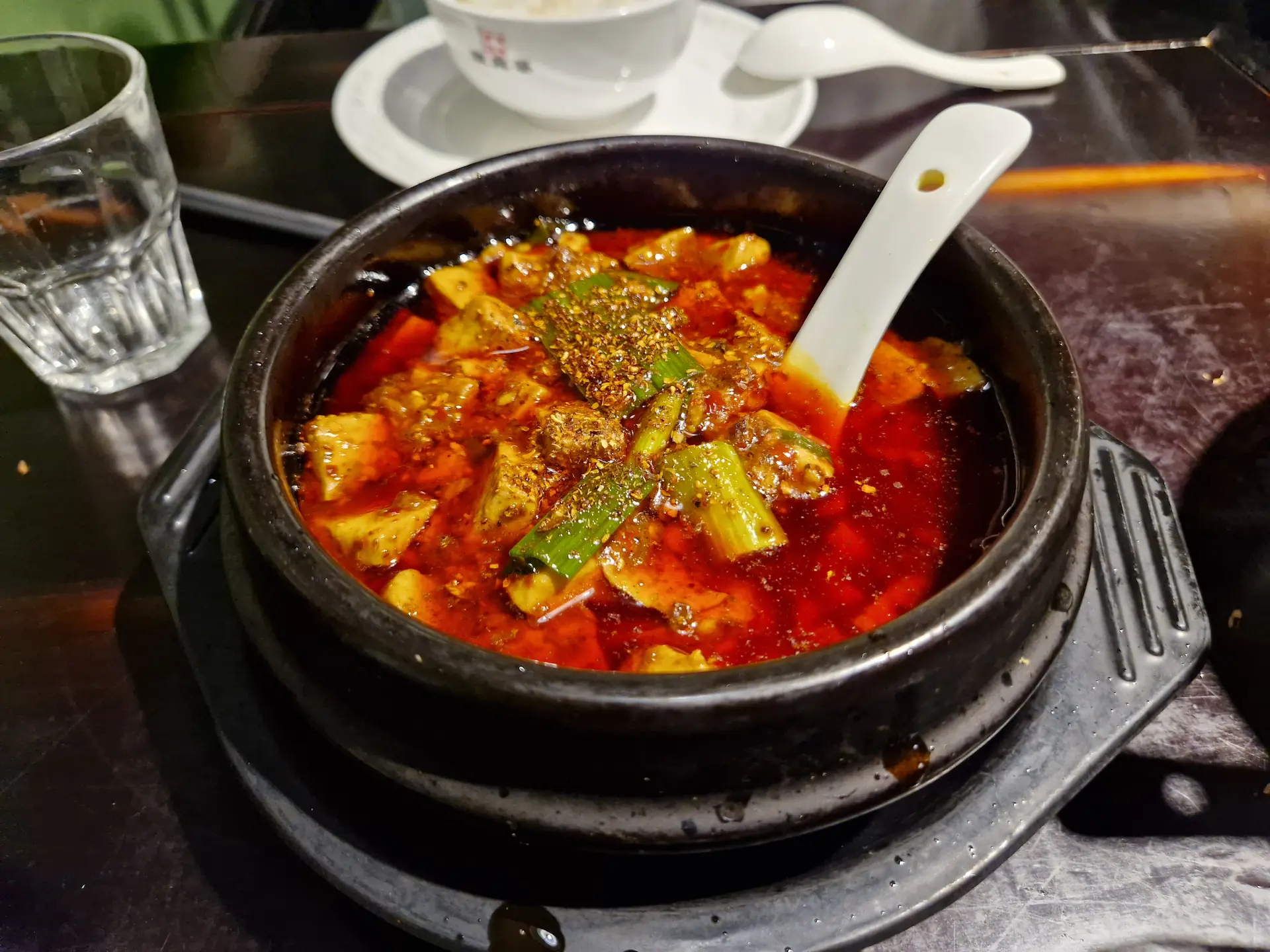 Dans un bol en terre cuite noire, le tofu soyeux baigne dans une sauce très rouge.