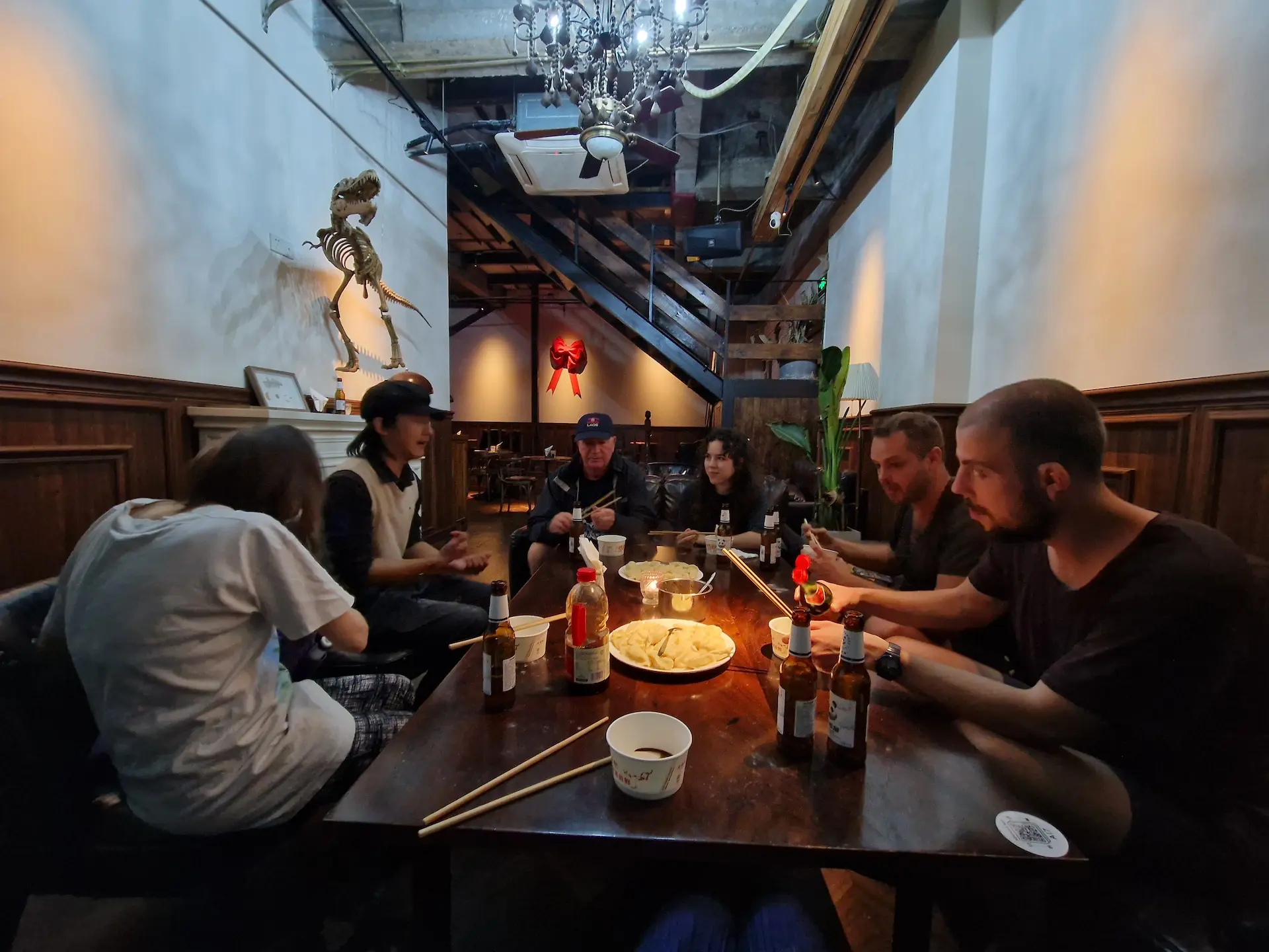 On est sept personnes assises autour d'une grande table à notre auberge. Au centre de la table, nos raviolis chinois sont prêts à être mangés.
