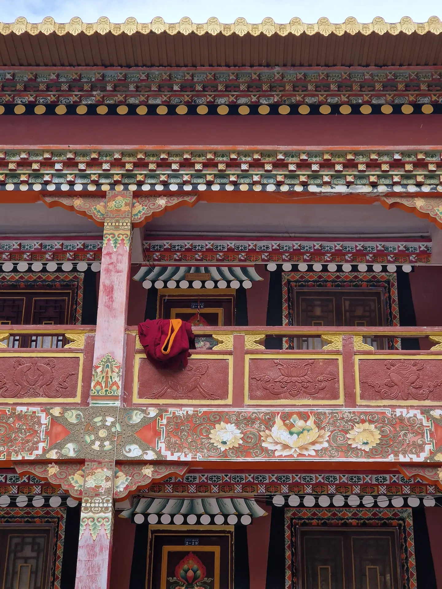 Des robes rouges sur une balustrade devant la chambre d'un moine