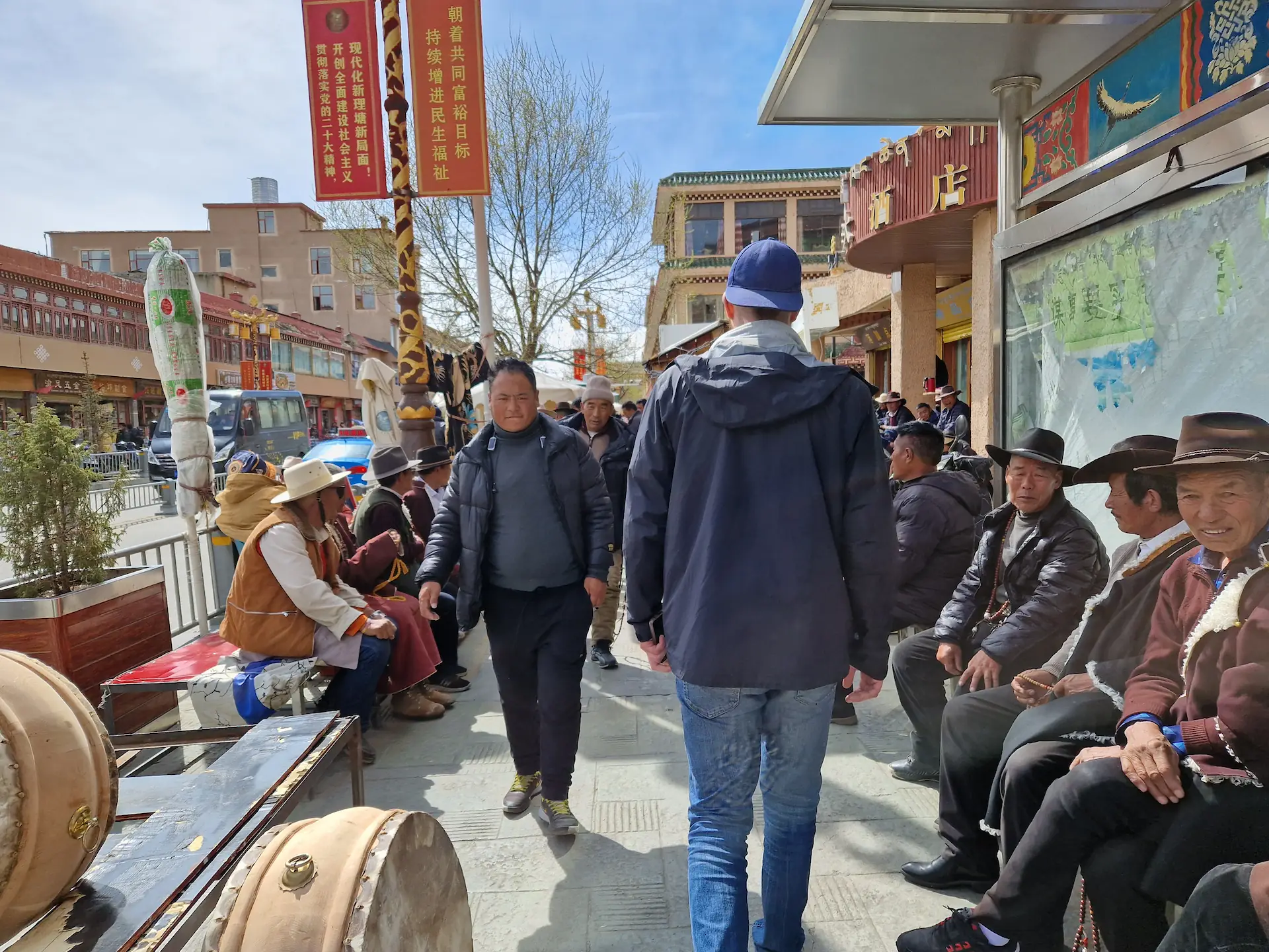 Robin en casquette passe entre deux bancs où sont assis plein de tibétains en chapeaux de cowboy