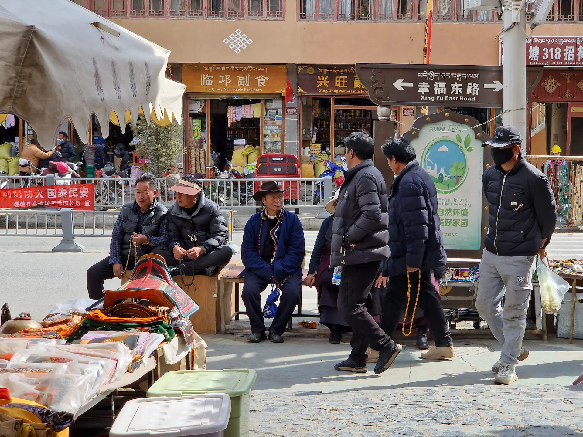 Cinq tibétains sur un banc et trois qui passent, un chapeau de cowboy et huit chapelets trengwa