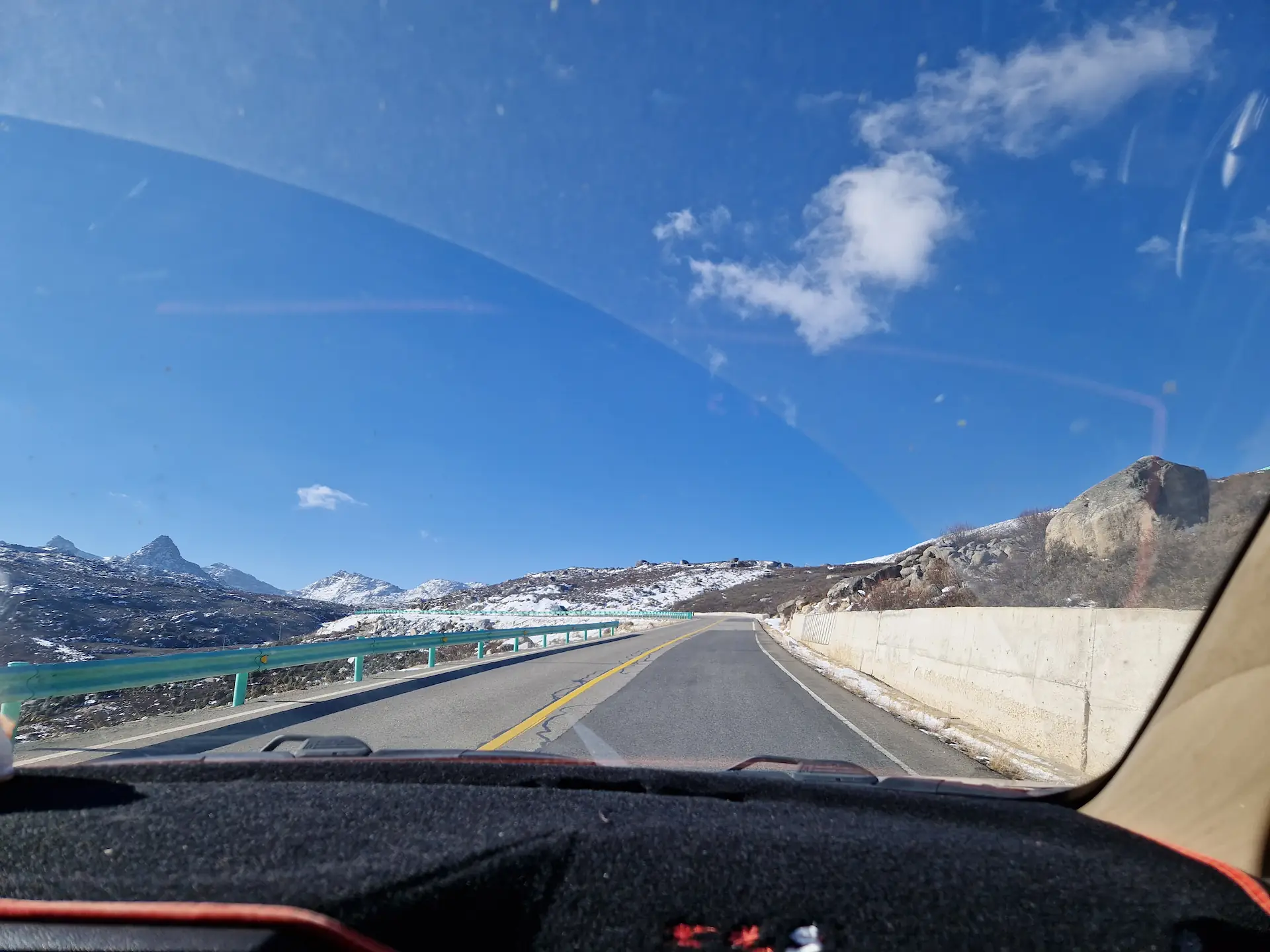 Le tableau de bord de la voiture avec une route vide et un paysage montagneux