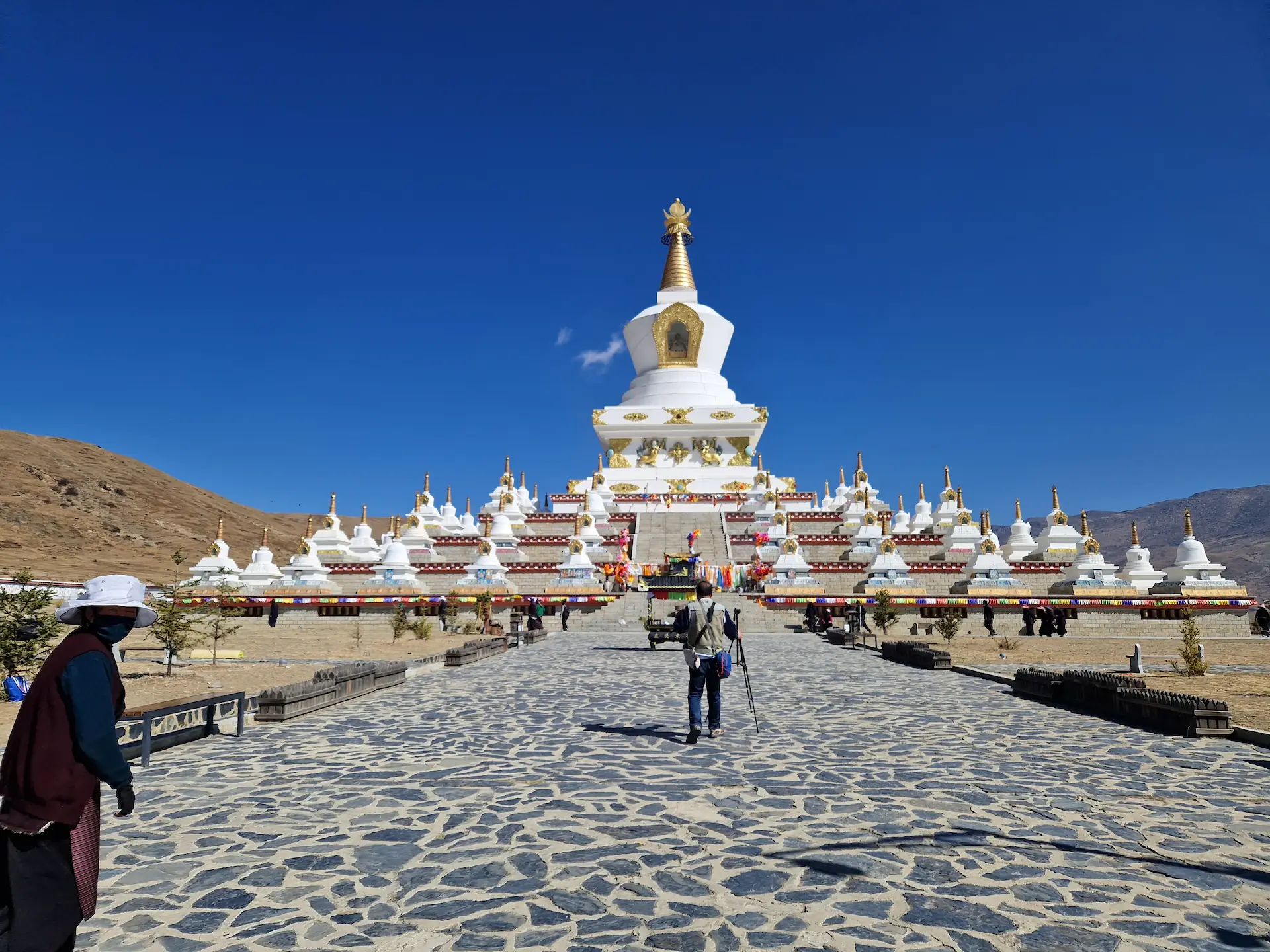 La pagode blanche de Daocheng dans un paysage de collines arides. Elle est blanche, décorée d'or