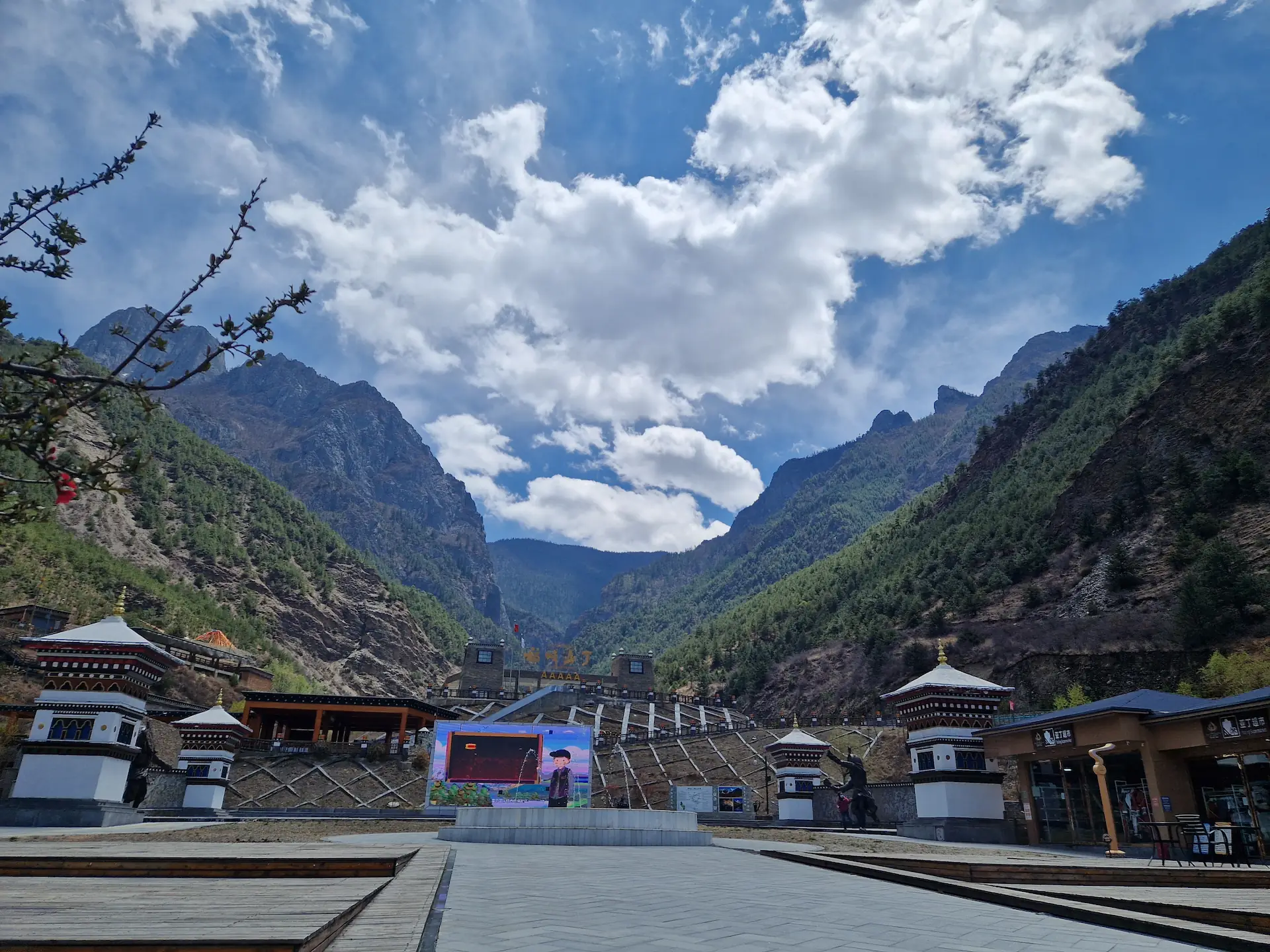 L'entrée de la réserve naturelle de Yading : une grande place bétonnée au pied d'une vallée, avec des magasins de souvenirs et un grand portail avec cinq A (AAAAA), le plus haut niveau du classement des attractions touristiques en Chine