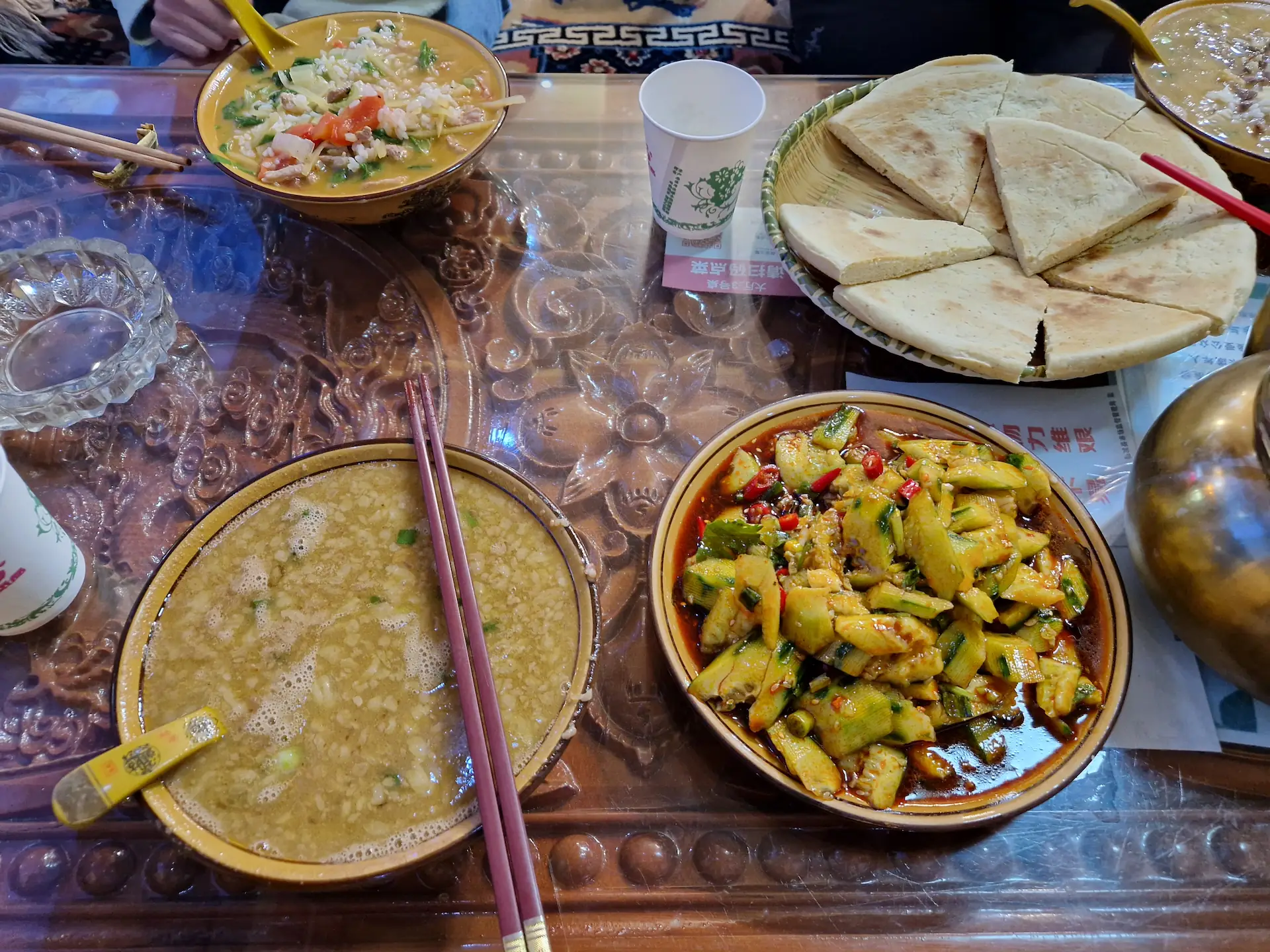Repas tibétain : soupe de beurre pour Robin, porridge pour Clara, galette et salade de concombres au piment à partager.