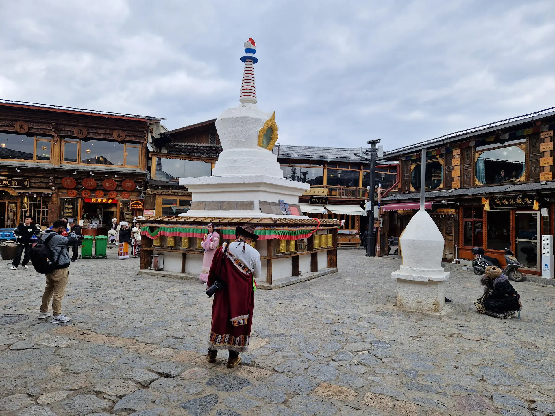 Une autre princesse en rose pose avec un moulin à prière devant un stupa.