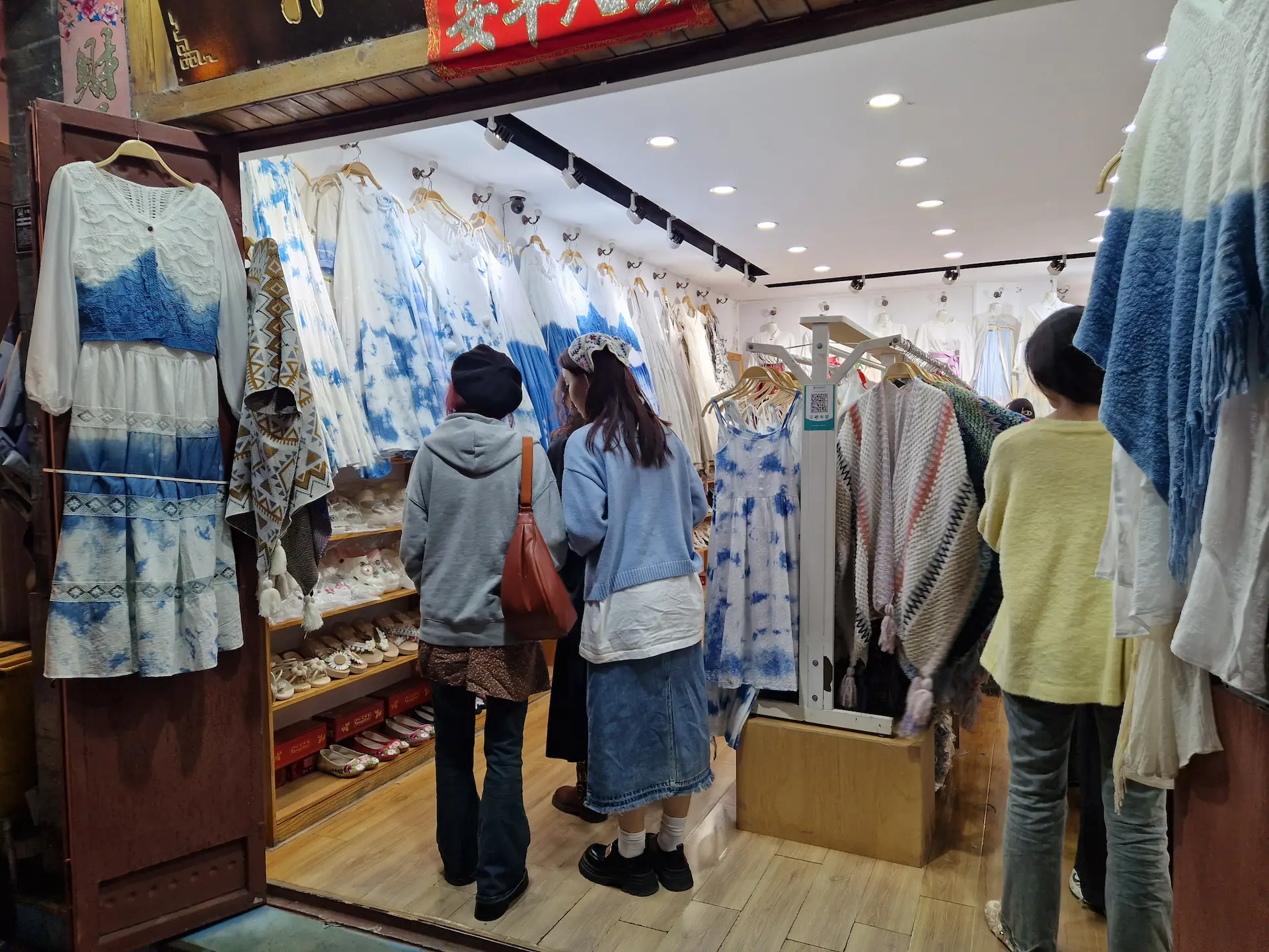 Un magasin d'habits 'hippies' teints en bleu et blanc. On voit des robes légères et des ponchos tissés. 