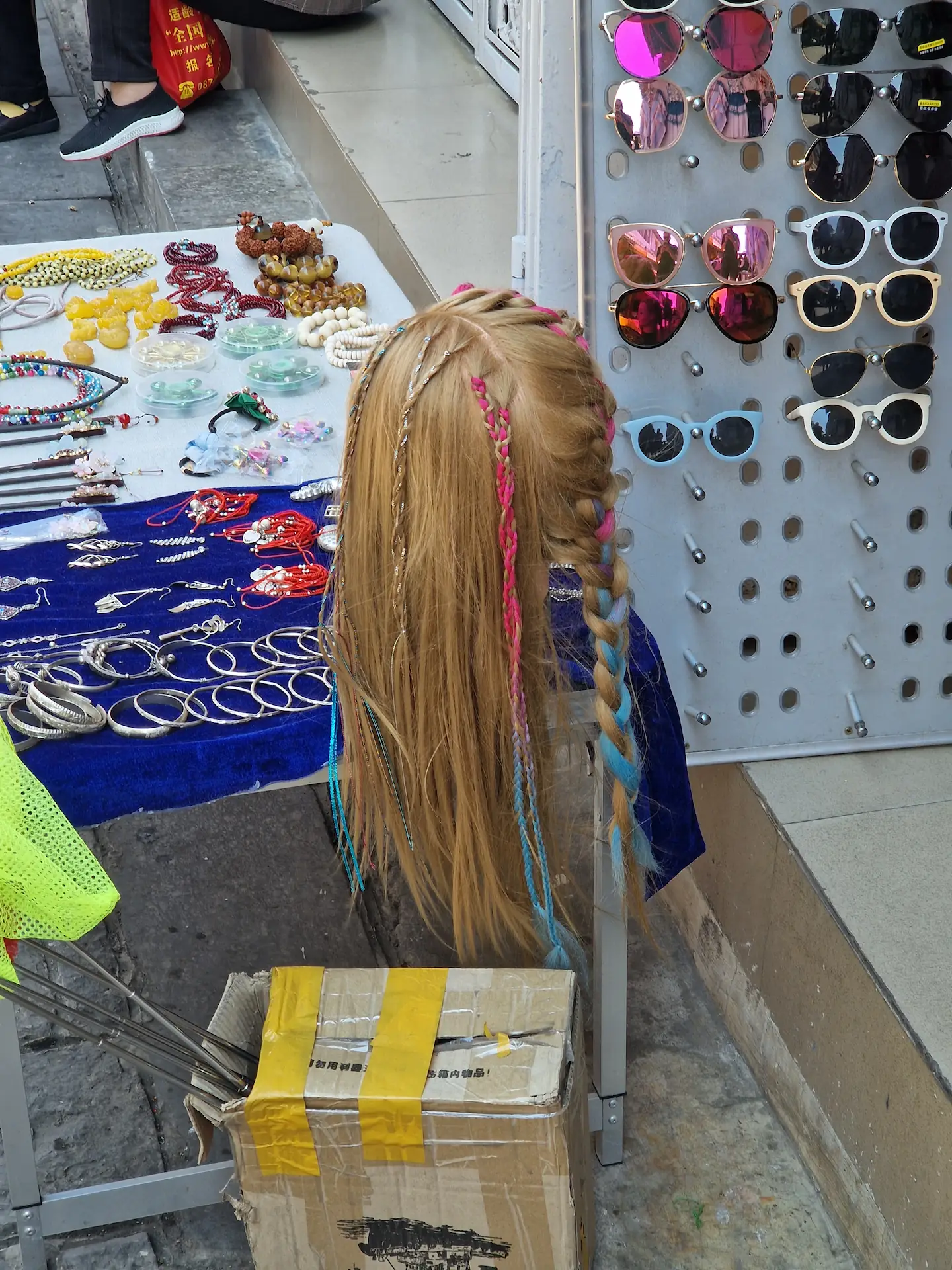Un stand dans la rue proposant de tresser des fils de couleurs dans vos cheveux.