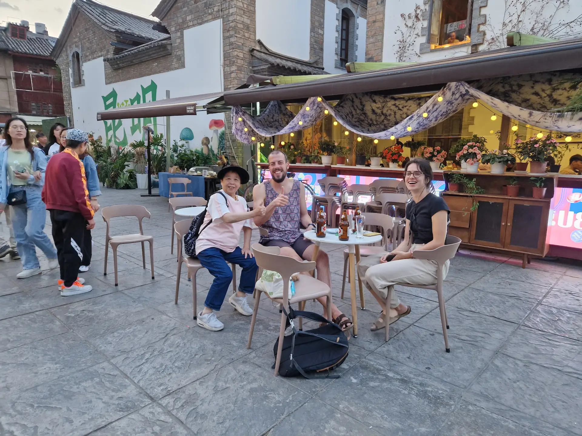 À notre petite table au milieu de la place, Robin, So et une touriste chinoise sourient à la caméra en faisant un pouce.