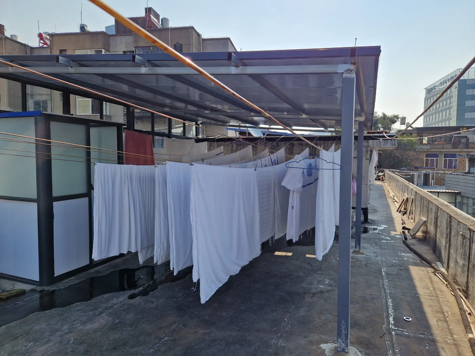 Sur le toit ouvert du bâtiment, les draps blancs de l'hôtel sèchent sur des fils tendus.