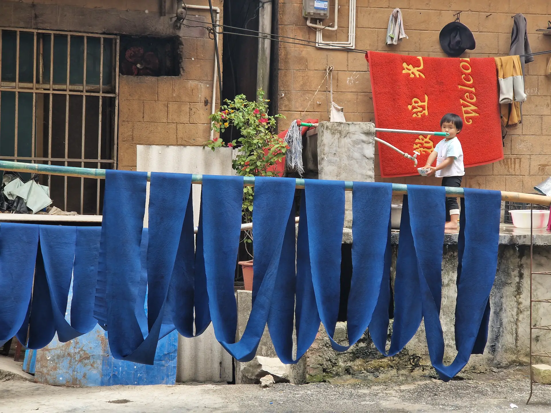 Une longue bande de tissu bleu sèche, accrochée à des branches de bambou.