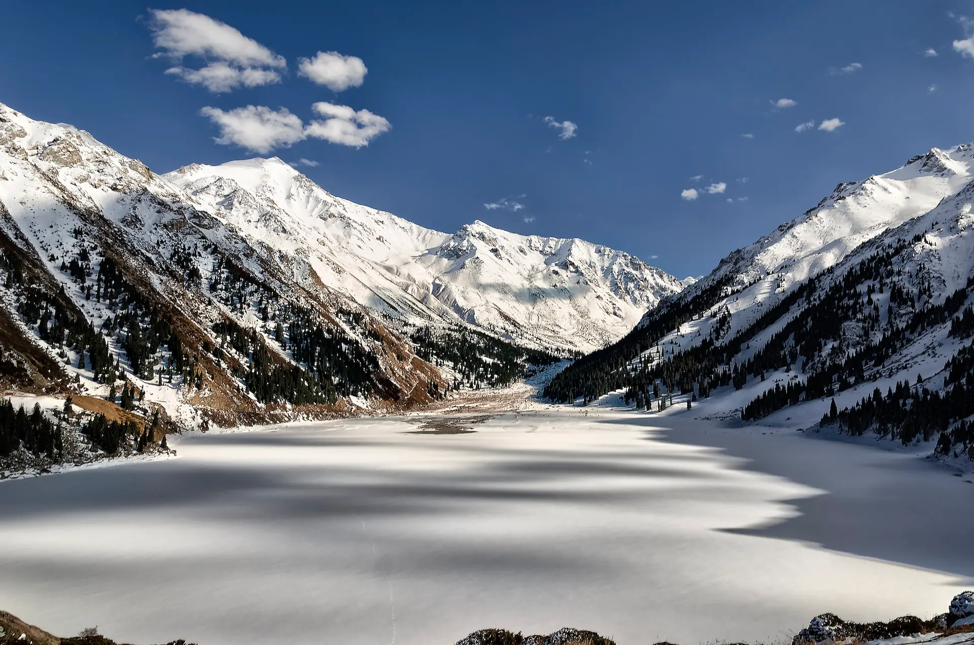 Un grand lac gelé entouré de montagnes enneigées